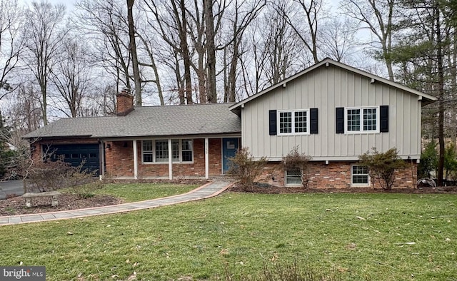 split level home featuring brick siding, an attached garage, a chimney, and a front yard