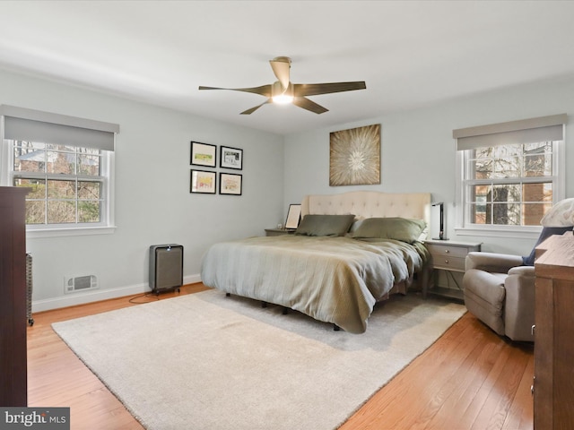 bedroom with baseboards, multiple windows, and light wood finished floors