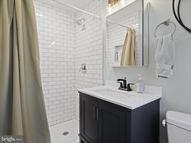 full bathroom featuring tiled shower, toilet, and vanity