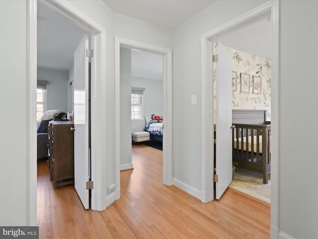 hall with light wood-style floors and baseboards