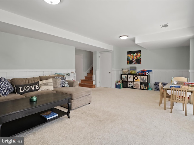 living room featuring stairway, carpet, visible vents, and a wainscoted wall