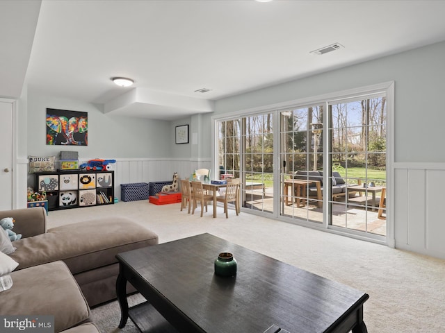 carpeted living room with visible vents, a wealth of natural light, and wainscoting