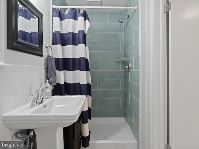 bathroom featuring tile walls, tasteful backsplash, a stall shower, and a sink