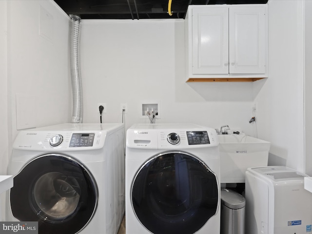 clothes washing area with separate washer and dryer, cabinet space, and a sink