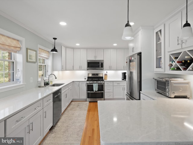 kitchen featuring light wood-style flooring, a sink, white cabinetry, appliances with stainless steel finishes, and a toaster