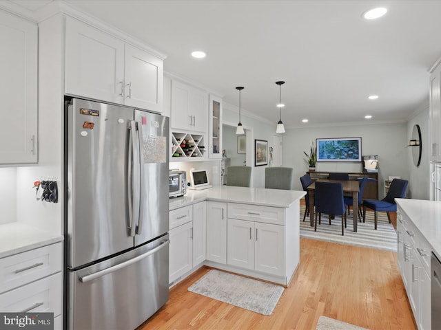 kitchen featuring a peninsula, ornamental molding, light countertops, white cabinets, and appliances with stainless steel finishes