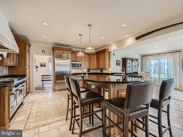 kitchen featuring stone tile flooring, a kitchen bar, custom exhaust hood, and premium appliances