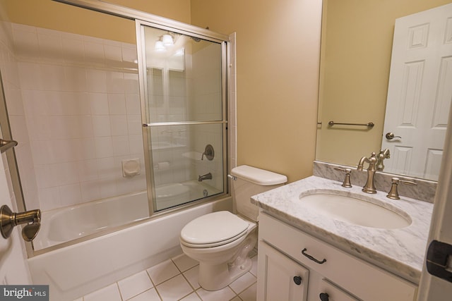 full bath featuring toilet, tile patterned flooring, combined bath / shower with glass door, and vanity