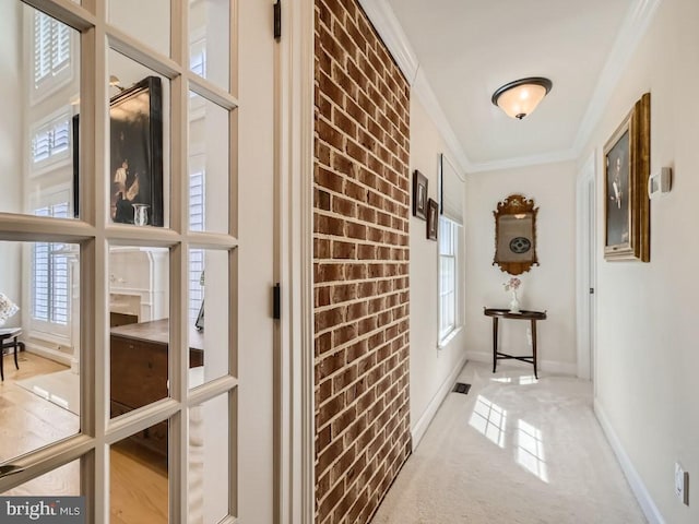 hall featuring baseboards, brick wall, a barn door, and crown molding