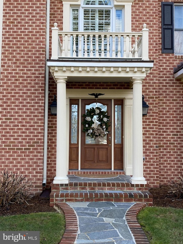 doorway to property featuring a balcony and brick siding