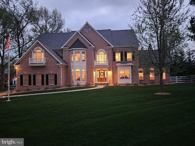 view of front of property with a front yard, brick siding, and fence