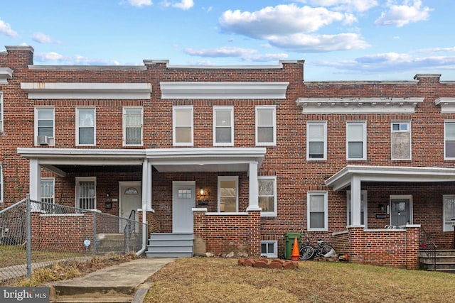 townhome / multi-family property featuring covered porch and brick siding