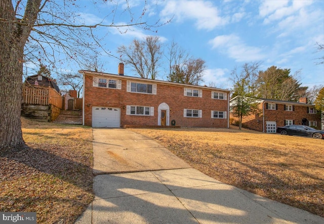 view of front of property with an attached garage, brick siding, driveway, a front lawn, and a chimney