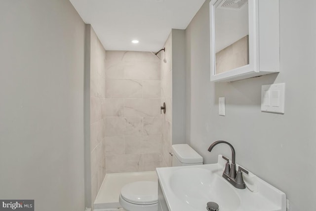 full bathroom featuring toilet, visible vents, a sink, and tiled shower