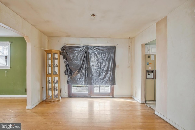 unfurnished dining area with baseboards, arched walkways, and wood finished floors