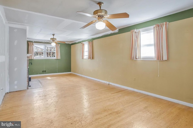 empty room featuring wood finished floors, a wealth of natural light, and baseboards