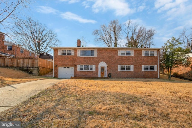 view of front of property featuring driveway, a chimney, an attached garage, a front yard, and brick siding