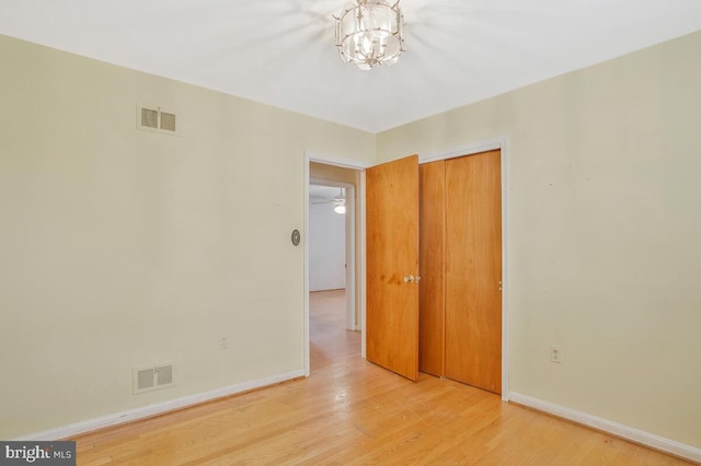 empty room with light wood-style floors, baseboards, and visible vents