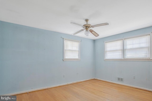 spare room with a ceiling fan, baseboards, visible vents, and light wood finished floors