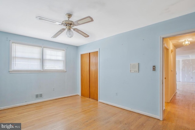 unfurnished bedroom with baseboards, visible vents, a ceiling fan, wood finished floors, and a closet