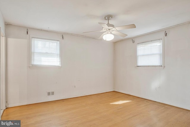 spare room with light wood-type flooring, baseboards, visible vents, and a wealth of natural light