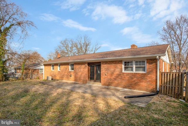 rear view of property with a chimney, fence, a yard, a patio area, and brick siding