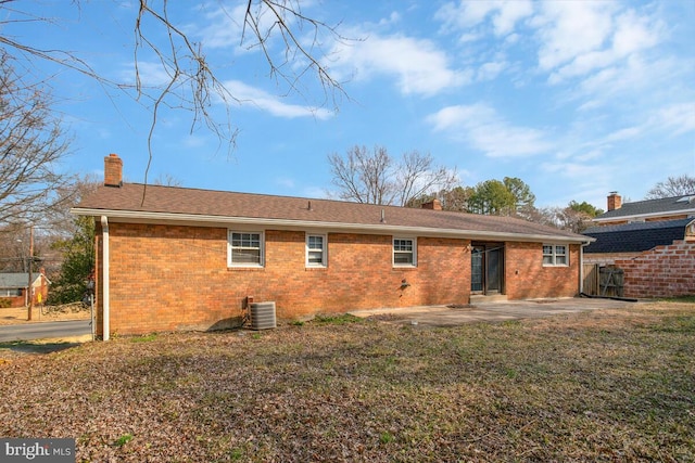 back of house featuring a patio area, a chimney, and brick siding