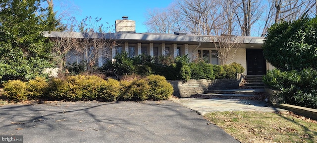 single story home with brick siding and a chimney