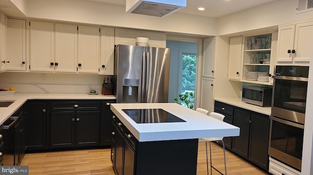 kitchen with stainless steel appliances, open shelves, light countertops, and dark cabinets