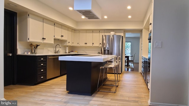 kitchen featuring dark cabinets, a center island, stainless steel appliances, light countertops, and white cabinetry