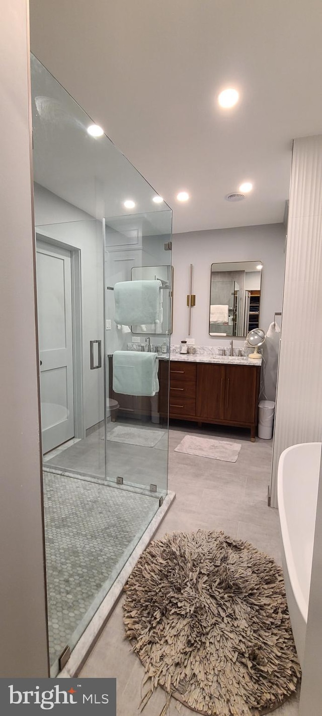 full bathroom with a stall shower, a freestanding tub, vanity, and recessed lighting