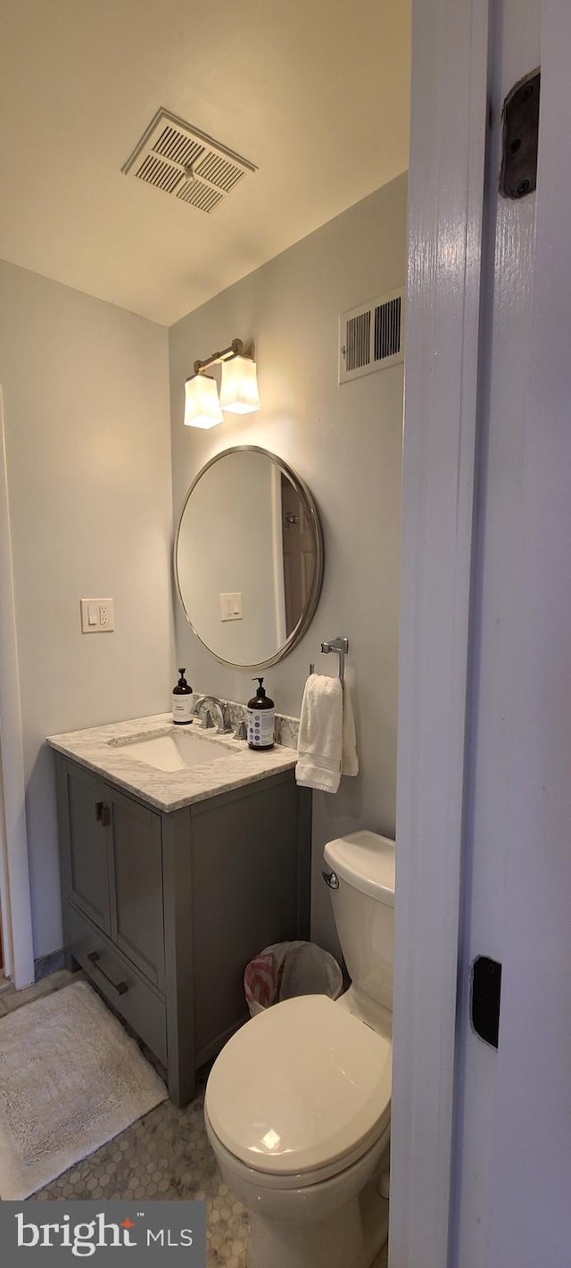 half bath featuring toilet, visible vents, and vanity