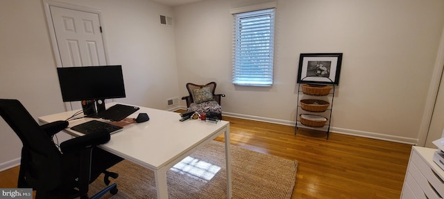 home office featuring light wood-style flooring, visible vents, and baseboards