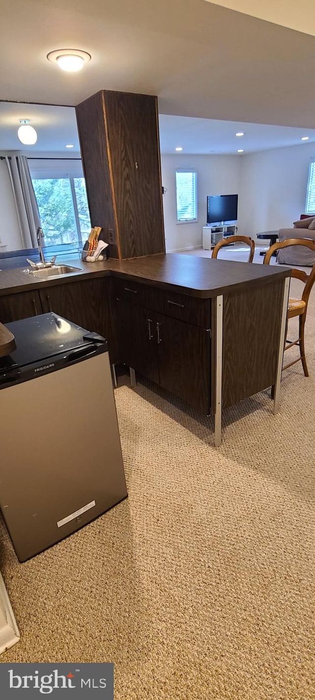 kitchen featuring dark countertops, a healthy amount of sunlight, dark brown cabinetry, and a sink