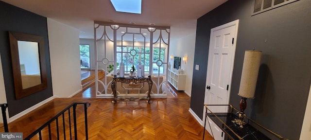 hallway with a skylight, visible vents, and baseboards