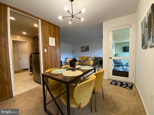 dining room featuring light carpet, a notable chandelier, and baseboards