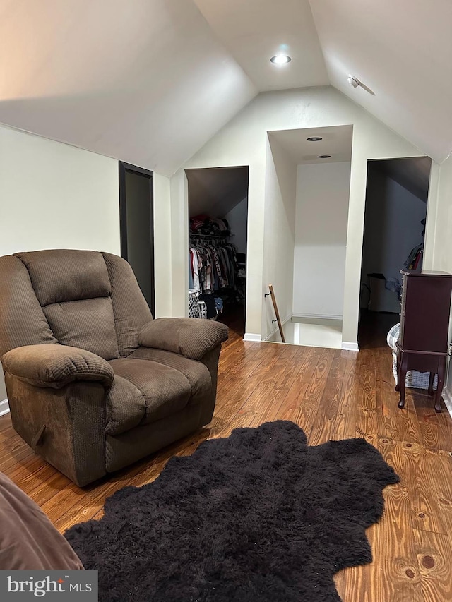 interior space with lofted ceiling, baseboards, an upstairs landing, and wood finished floors