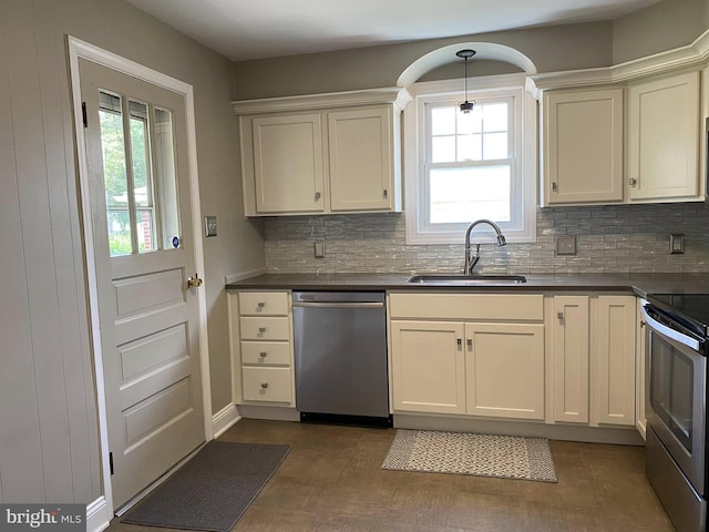 kitchen with stainless steel appliances, dark countertops, a sink, and a healthy amount of sunlight