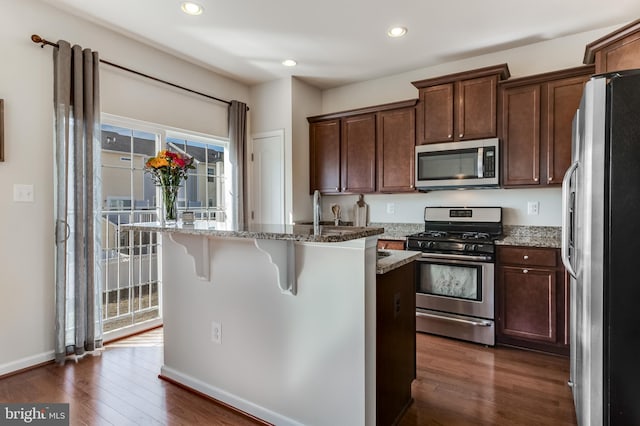 kitchen with light stone countertops, stainless steel appliances, dark wood-style flooring, and recessed lighting