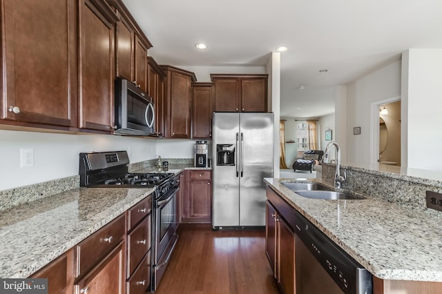 kitchen with light stone counters, recessed lighting, dark wood-type flooring, a sink, and appliances with stainless steel finishes