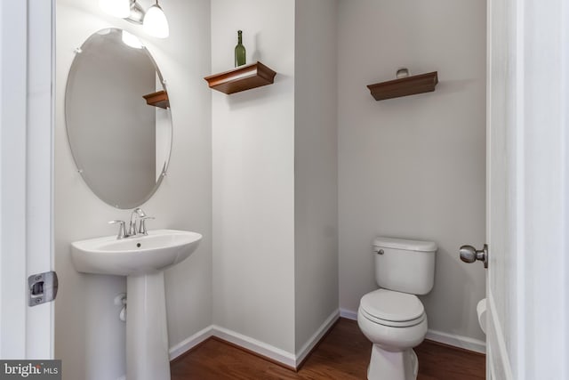 bathroom featuring toilet, a sink, baseboards, and wood finished floors