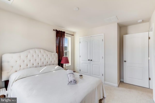 bedroom with a closet, light carpet, and baseboards