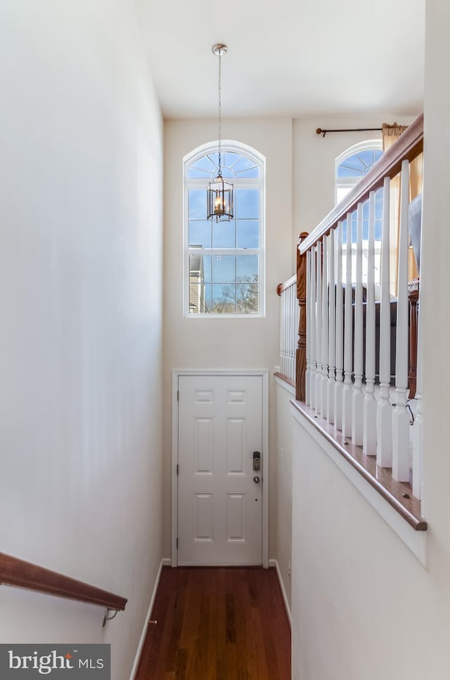 doorway to outside with a notable chandelier, stairway, baseboards, and wood finished floors