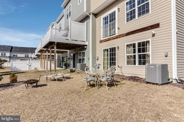 rear view of property featuring central AC unit, an outdoor fire pit, and fence