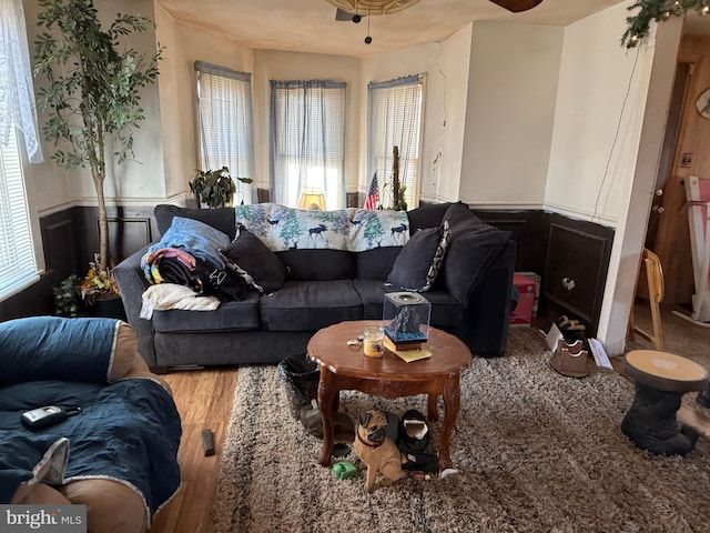 living area with a healthy amount of sunlight, wood finished floors, and wainscoting