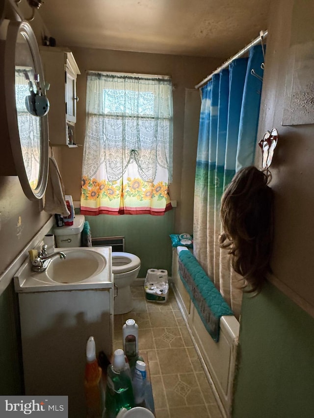 bathroom featuring toilet, shower / bath combo with shower curtain, and vanity