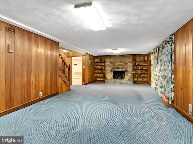 unfurnished living room featuring stairs, built in features, wood walls, and carpet flooring