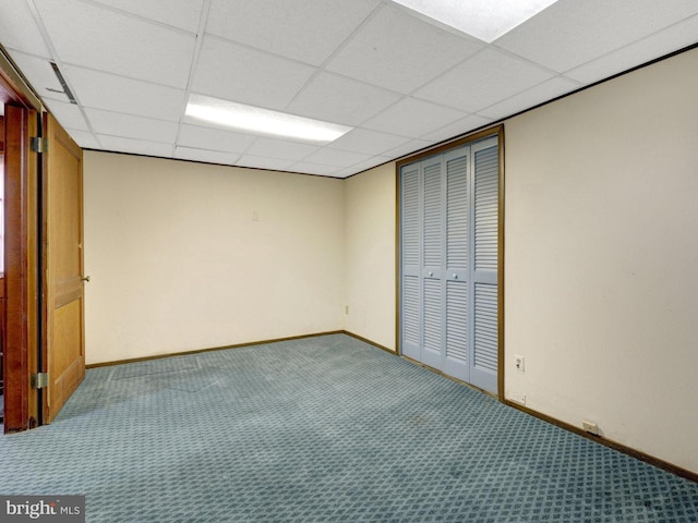 interior space featuring a drop ceiling, baseboards, and carpet floors