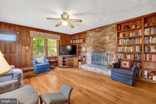 living room featuring light wood finished floors, baseboard heating, wood walls, and built in features