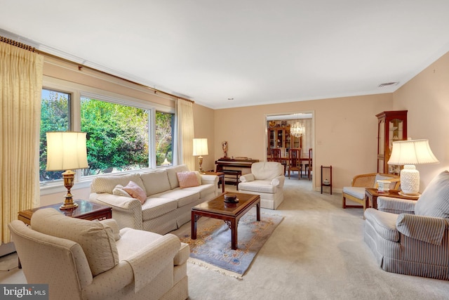 living area featuring visible vents, light colored carpet, a chandelier, and crown molding